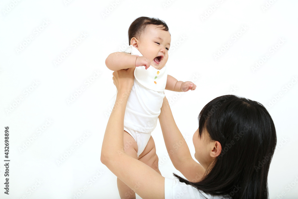 白背景で赤ちゃんを抱き向き合い、あやすお母さんの上半身。母性,幸福,愛情,育児イメージ