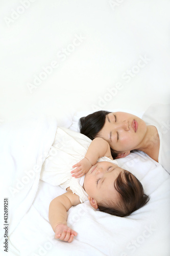 Mom taking a nap with her baby on a background of white sheets