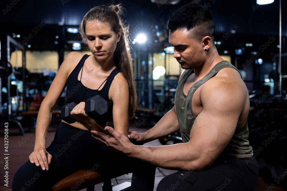 Young beautiful woman doing exercises with personal trainer in gym. Young beautiful woman doing exercises with personal trainer in gym.