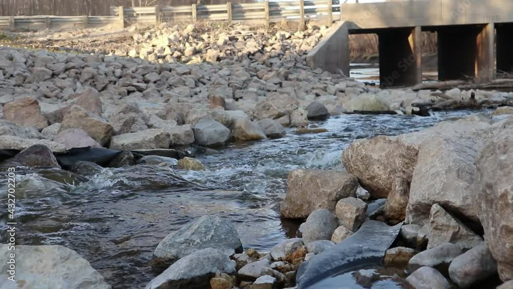A small river flows between the stones with bridge background. A small river flows between the stones with bridge background.