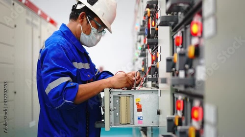 An industrial electrician is inspecting the electrical control cabinet, industrial operation concept and technology. photo