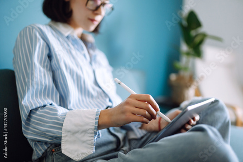 Young woman using tablet, spending leisure time chatting in social network, freelancer working online. Working from home in quarantine lockdown. Education online.