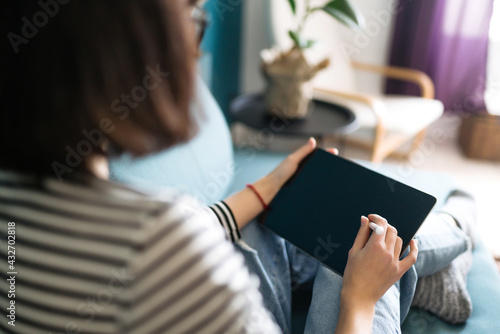 Quadro su tela Young woman using tablet, spending leisure time chatting in social network, freelancer working online