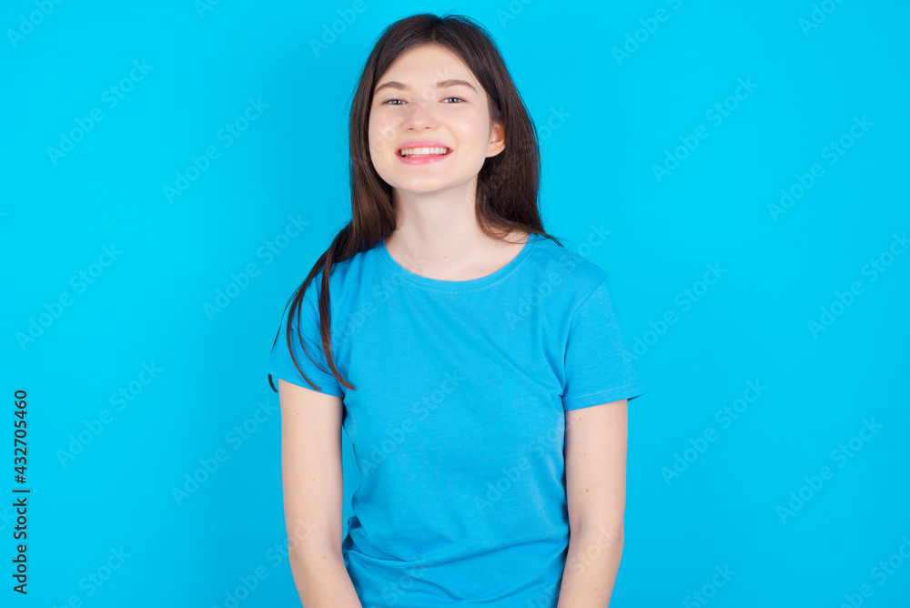 young beautiful Caucasian woman wearing blue T-shirt over blue wall with nice beaming smile pleased expression. Positive emotions concept young beautiful Caucasian woman wearing blue T-shirt over blue wall with nice beaming smile pleased expression. Positive emotions concept