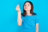 young beautiful Caucasian woman wearing blue T-shirt over blue wall Doing Italian gesture with hand and fingers confident expression