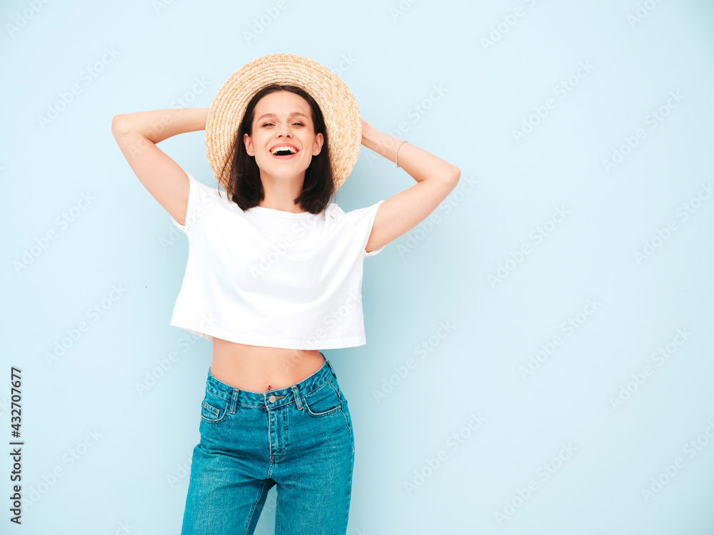 Portrait of young beautiful smiling female in trendy summer hipster clothes. Sexy carefree woman posing near blue wall in studio. Positive model having fun in hat. Cheerful and happy Portrait of young beautiful smiling female in trendy summer hipster clothes. Sexy carefree woman posing near blue wall in studio. Positive model having fun in hat. Cheerful and happy