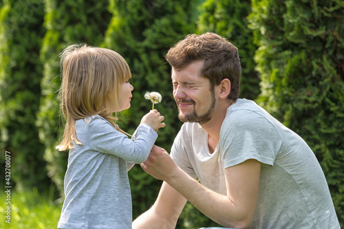Father and daughter blowing dandelion on summer garden. Happy family.