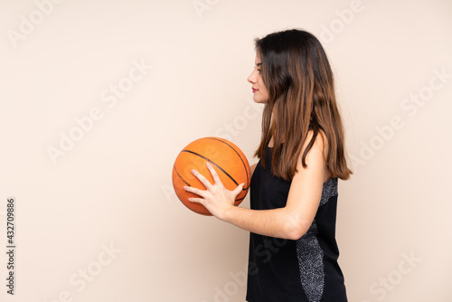 Young caucasian woman isolated on beige background playing basketball