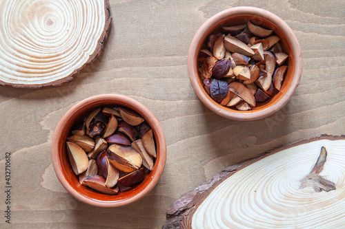 Fototapeta Naklejka Na Ścianę i Meble -  Chopped cut avocado seeds in clay bowls top view. Drying hass avocado seeds. Zero waste concept.