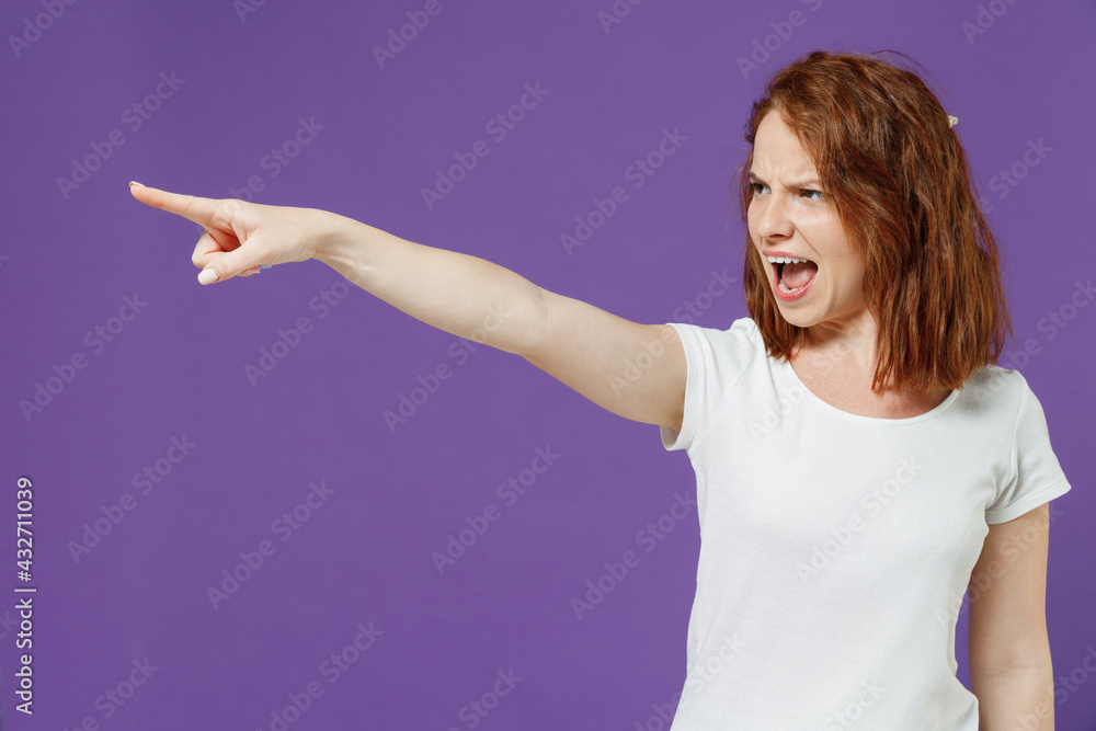 Young angry indignant caucasian woman 20s wearing white basic blank print design t-shirt point index finger aside command do it scream shout isolated on dark violet color background studio portrait Young angry indignant caucasian woman 20s wearing white basic blank print design t-shirt point index finger aside command do it scream shout isolated on dark violet color background studio portrait