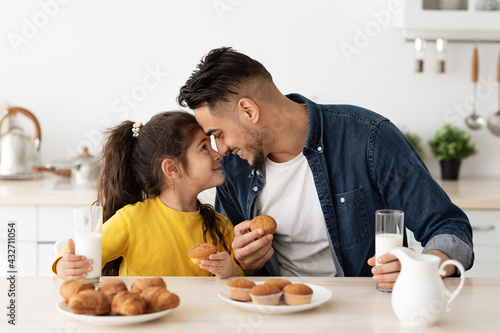 Happy Loving Arab Father And Little Daughter Eating Snacks In Kitchen Together