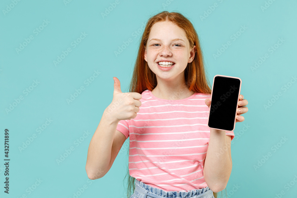 Little redhead kid girl 12-13 years old in pink striped tshirt hold mobile cell phone with blank screen workspace area, thumb up gesture isolated on pastel blue background Lifestyle childhood concept Little redhead kid girl 12-13 years old in pink striped tshirt hold mobile cell phone with blank screen workspace area, thumb up gesture isolated on pastel blue background Lifestyle childhood concept