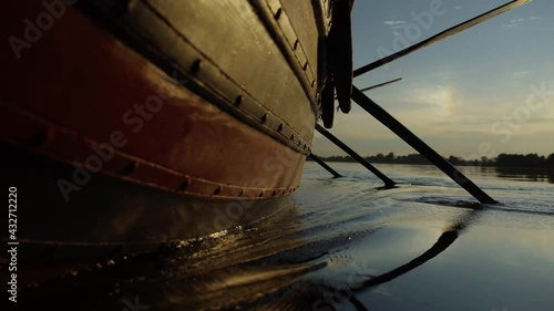 Viking boat oars plunge into water, beautiful spray, sunset, forest
