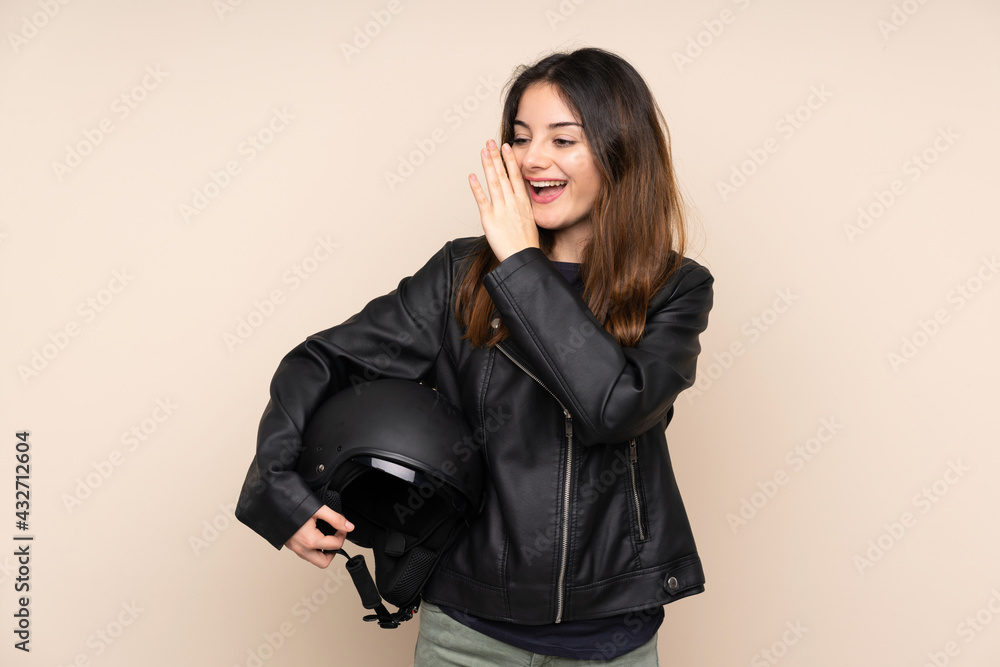 Woman with a motorcycle helmet isolated on beige background shouting with mouth wide open Woman with a motorcycle helmet isolated on beige background shouting with mouth wide open