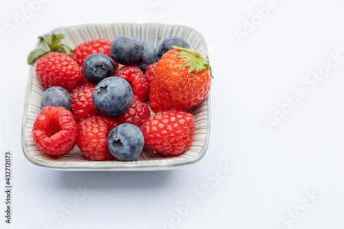 Strawberry raspberry and blueberry on a plate on white background