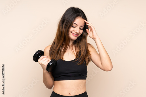 Young sport woman making weightlifting isolated on beige background laughing