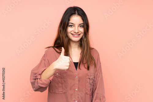 Young caucasian woman isolated on pink background giving a thumbs up gesture