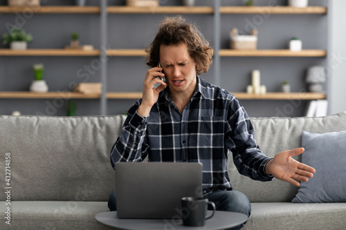 Discontented Man Talking On Phone Having Problem At Home