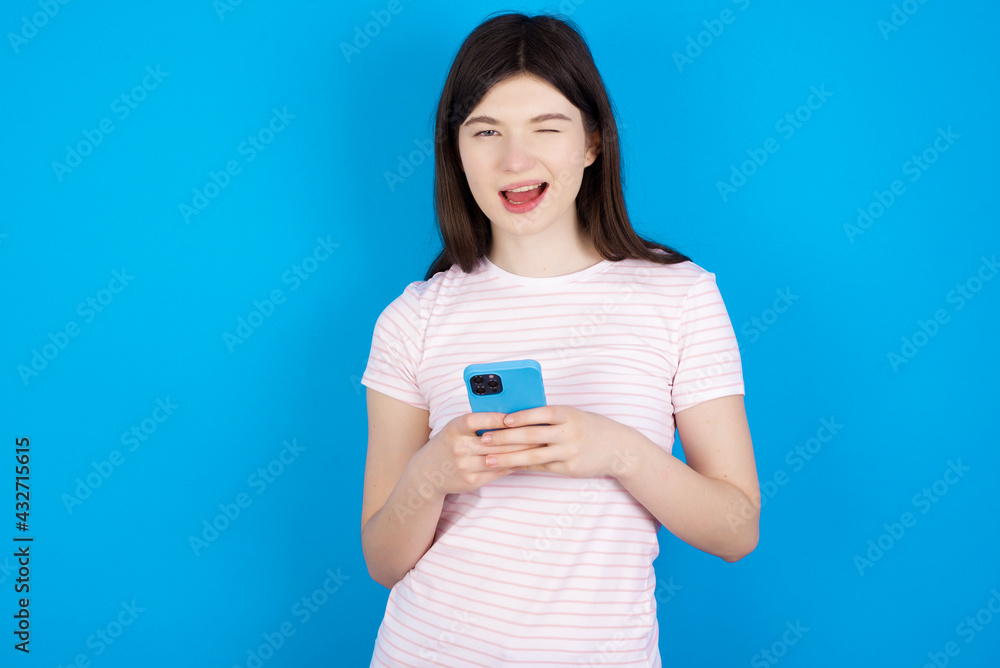 young beautiful Caucasian woman wearing stripped T-shirt over blue wall taking a selfie celebrating success young beautiful Caucasian woman wearing stripped T-shirt over blue wall taking a selfie celebrating success