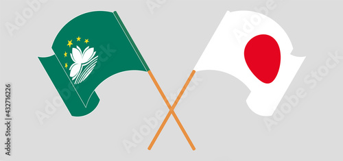 Crossed and waving flags of Macau and Japan