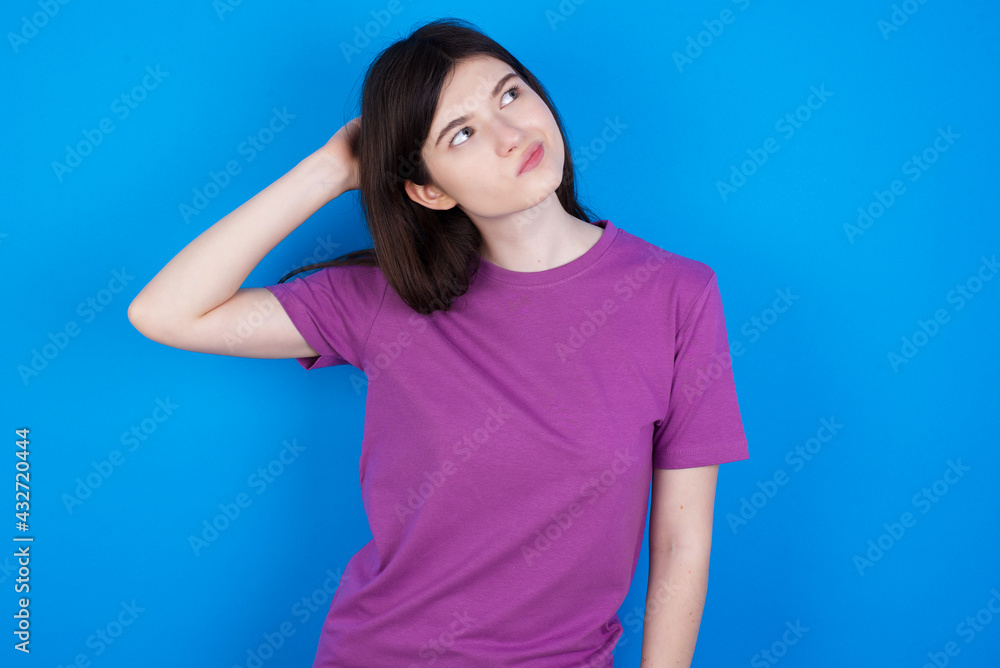 Φωτογραφία young beautiful Caucasian woman wearing purple T-shirt over blue wall confuse and wonder about question