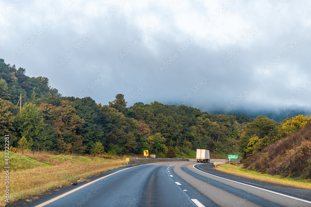 Fog mist dark stormy cloudy weather covering forest trees in autumn fall at sunrise in rural countryside in Virginia near Front Royal with cars in traffic morning Fog mist dark stormy cloudy weather covering forest trees in autumn fall at sunrise in rural countryside in Virginia near Front Royal with cars in traffic morning