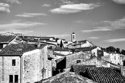 stone houses and belfry with clock in village of Balazuc