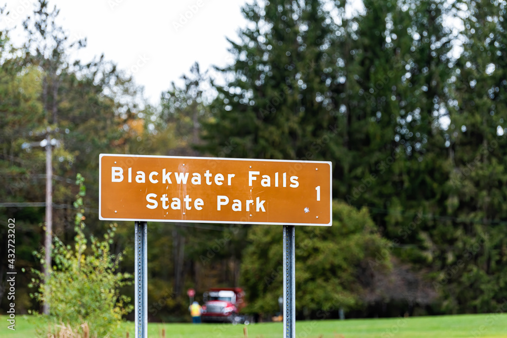 Davis, West Virginia and sign on road for Blackwater Falls one mile left on street in Canaan valley area in fall autumn season with trees in bokeh background