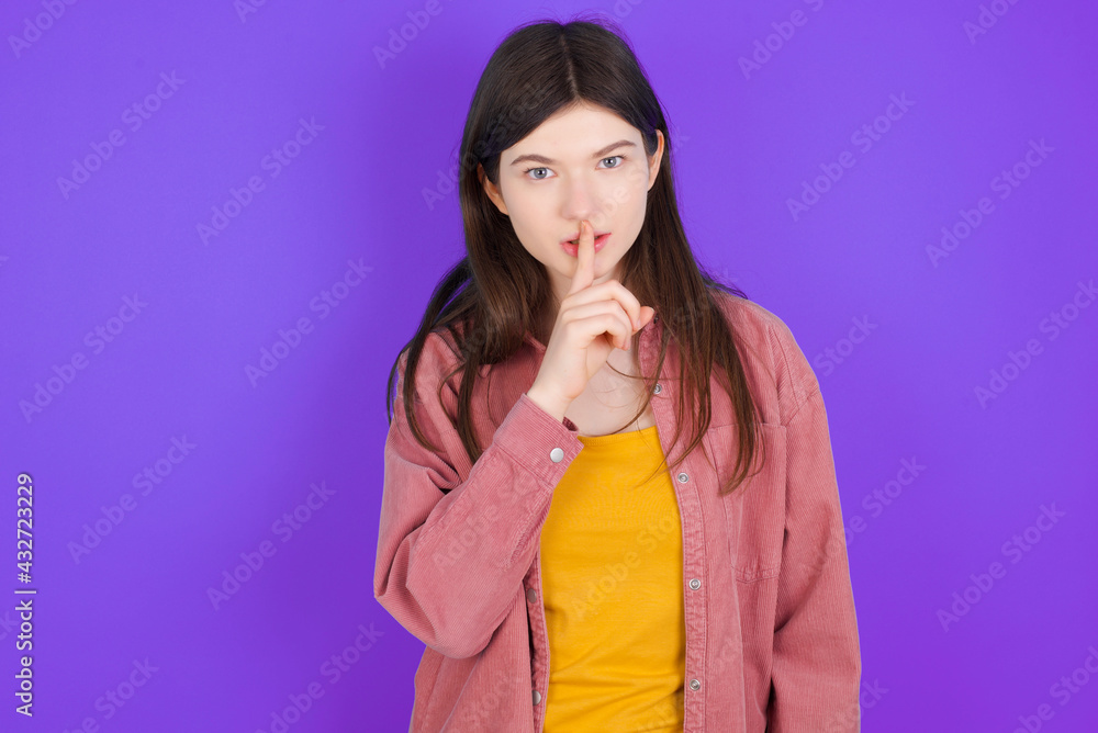 young beautiful Caucasian woman wearing casual clothes over purple wall makes hush gesture, asks be quiet. Don't tell my secret or not speak too loud, please! young beautiful Caucasian woman wearing casual clothes over purple wall makes hush gesture, asks be quiet. Don't tell my secret or not speak too loud, please!