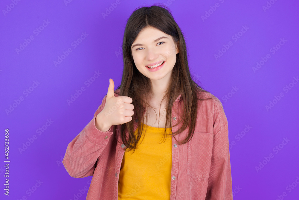 young beautiful Caucasian woman wearing casual clothes over purple wall giving thumb up gesture, good Job! Positive human emotion facial expression body language. young beautiful Caucasian woman wearing casual clothes over purple wall giving thumb up gesture, good Job! Positive human emotion facial expression body language.