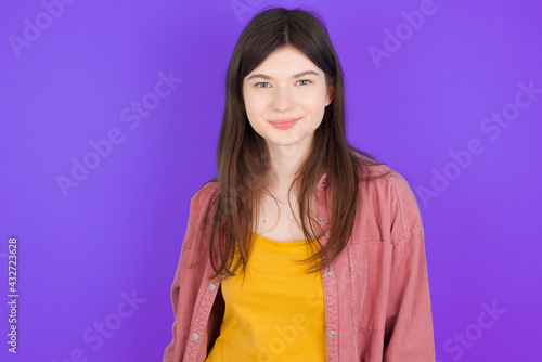 Happy young beautiful Caucasian woman wearing casual clothes over purple wall looking at camera with charming cute smile.