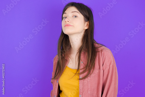 young beautiful Caucasian woman wearing casual clothes over purple wall with snobbish expression curving lips and raising eyebrows, looking with doubtful and skeptical expression, suspect and doubt.