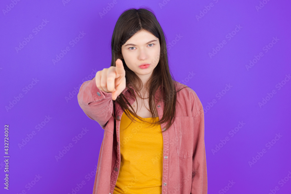 Cheerful young beautiful Caucasian woman wearing casual clothes over purple wall indicates happily at you, chooses to compete, has positive expression, makes choice. Cheerful young beautiful Caucasian woman wearing casual clothes over purple wall indicates happily at you, chooses to compete, has positive expression, makes choice.