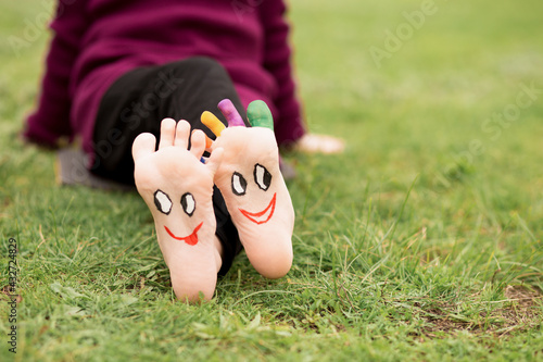 Wallpaper Mural Child have fun outdoor on grass. Feet of child with painted smile faces. Torontodigital.ca