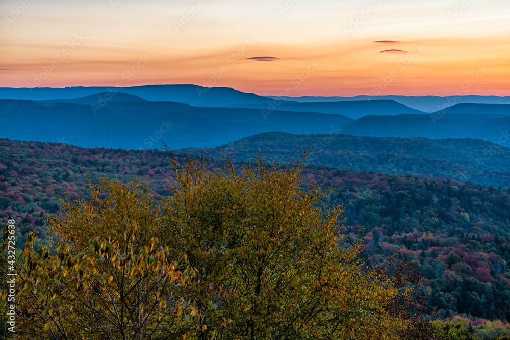 West Virginia Monongahela national forest overlook with colorful orange yellow clouds above mountains horizon in autumn with colorful tree foliage at morning sunrise in Highland Scenic Highway