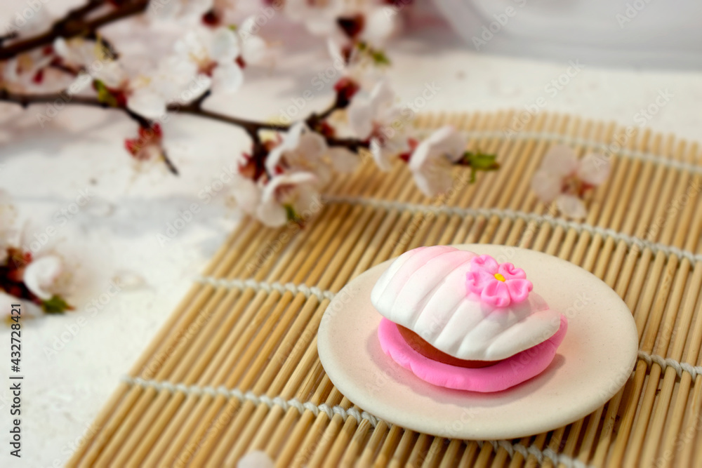Japanese traditional confectionery mochi with blossom on bamboo mat. Healthy vegan rice sweets. Beautiful wagashi.  Spring romance concept for restaurant menu, receipt instruction.