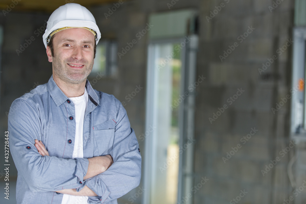 happy young man builder in helmet standing with arms crossed happy young man builder in helmet standing with arms crossed
