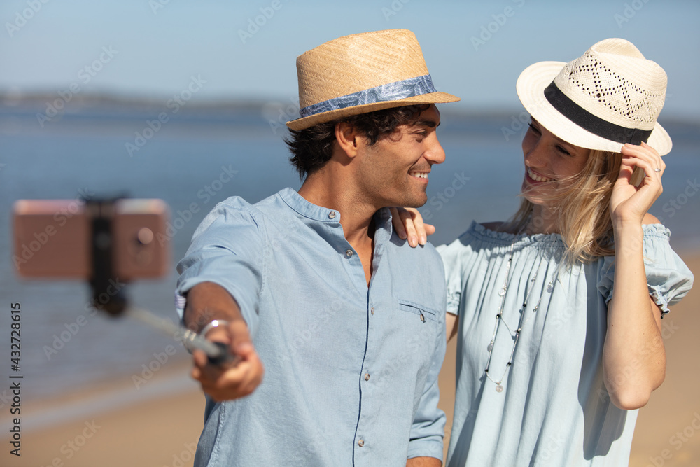 pretty young loving couple taking selfie together on sea beach