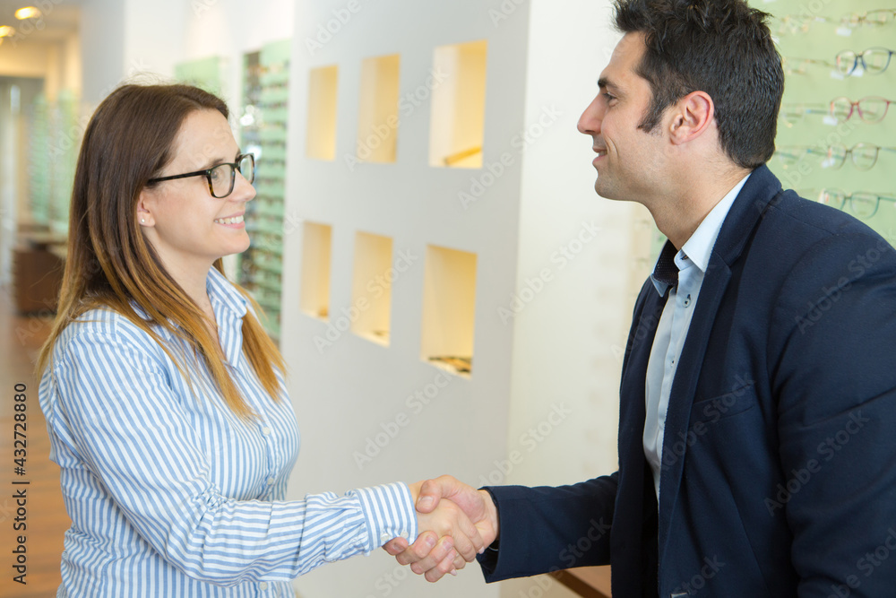 portrait of optician shaking clients hand portrait of optician shaking clients hand