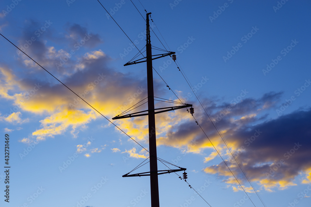 A large electrical pole with wires in the evening at sunset. A large electrical pole with wires in the evening at sunset.