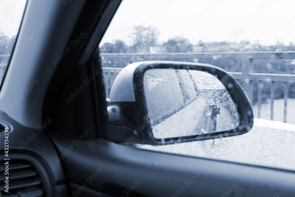 Photo of the reflection of the rearview mirror of the car during the rain through the wet glass.