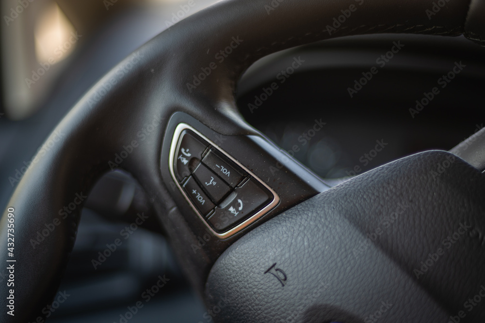 Steering wheel in a car with control buttons.