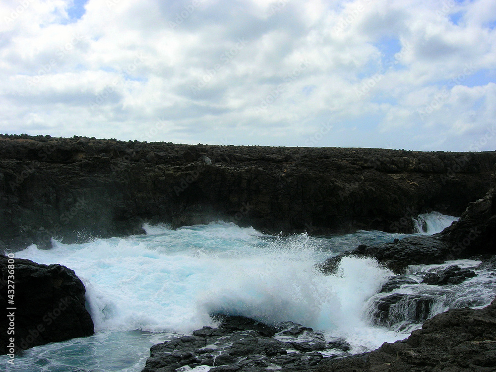Splashes and waterfalls left by the breaking wave on the rocks of the cave of the blue eye of Barracona, natural pool, Sal Island, Cape Verde Splashes and waterfalls left by the breaking wave on the rocks of the cave of the blue eye of Barracona, natural pool, Sal Island, Cape Verde