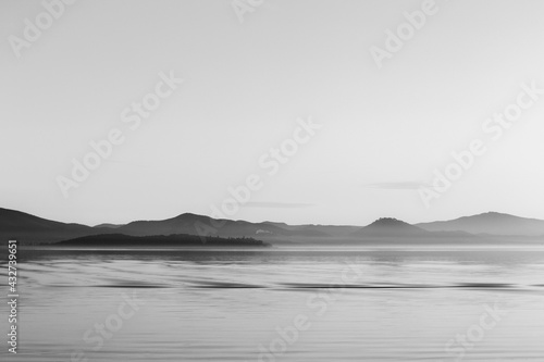 View of Trasimeno lake in Umbria, Italy, with empty sky and beautiful water reflections with ripples. Otherworldly stillness. © Massimo