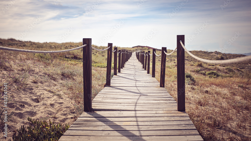 Beautiful horizontal shot of a long bridge. Wooden footpath. Wild sandy landscape with part of the dunes of Cresmin
