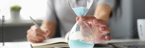 Business woman putting hourglass on digital tablet closeup