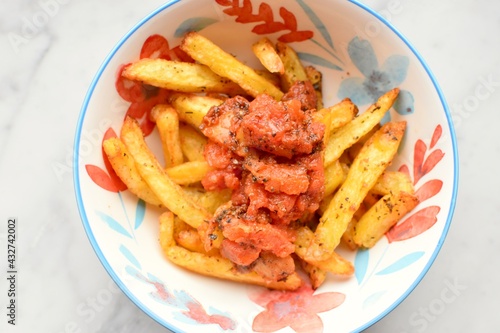 Bowl of fries with tomato sauce on top