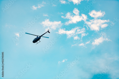 Helicopter against the sky. A small helicopter flies forward. A shot of a helicopter in motion with only two blades.