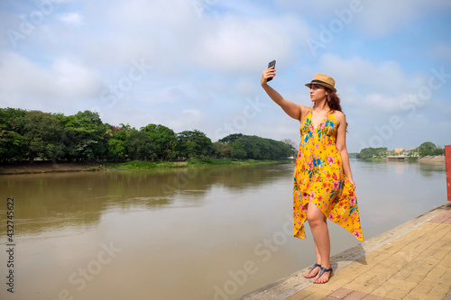 Obraz na płótnie woman in yellow dress taking a selfie by the river w salonie