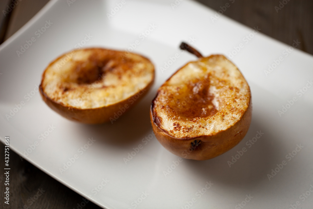 Baked pears with cinnamon and honey in a white plate close up